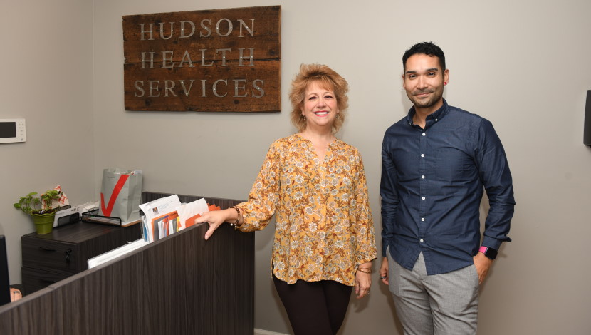Three people pose at a front desk