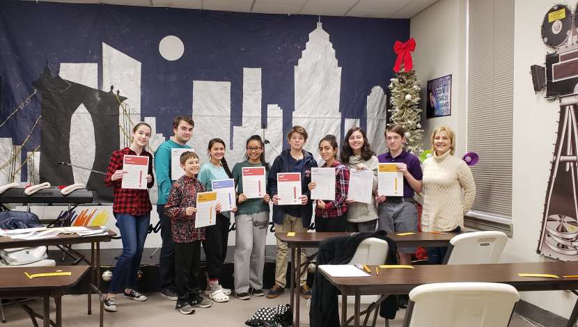 Teacher and students pose for picture in front of stage set