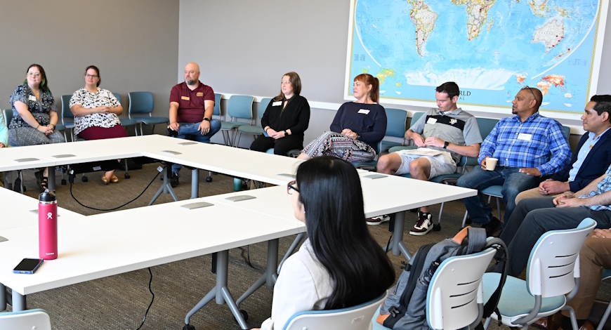 Faculty sit at a large sqaure table for a talk