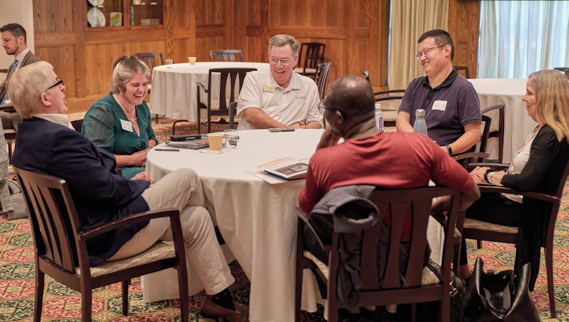 Faculty sit and talk at a circle table